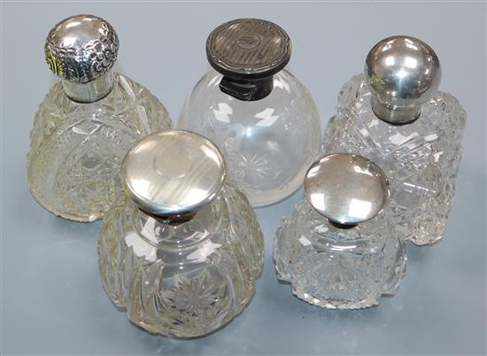 Five assorted early 20th century silver mounted glass scent bottles including Walker & Hall, Birmingham, 1915, tallest 11.8cm.